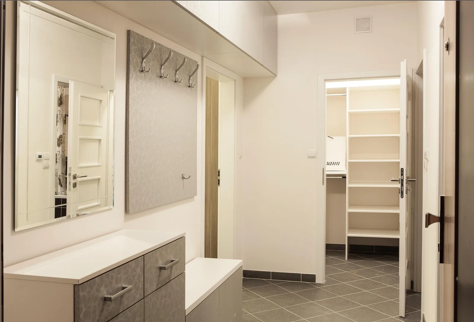 Closet empotrado con estantería abierta, espejo y perchero en un pasillo